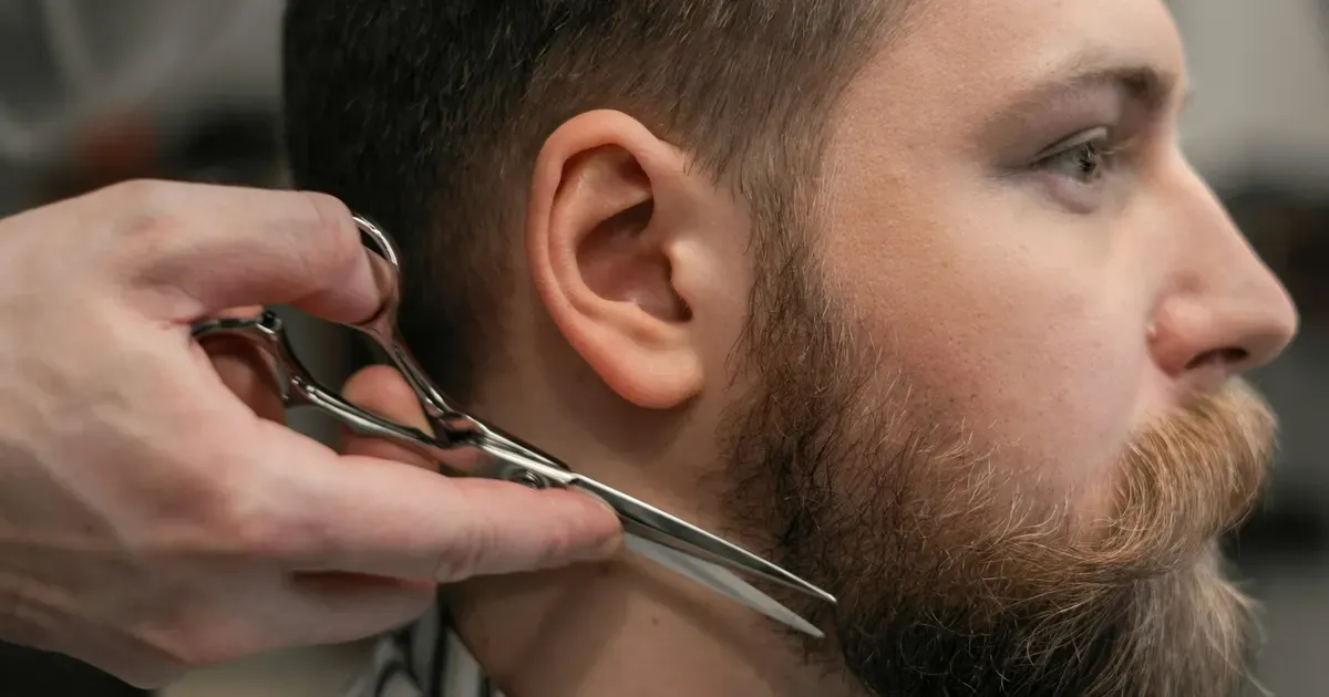 Barbeiro a aparar uma barba farta com tesoura