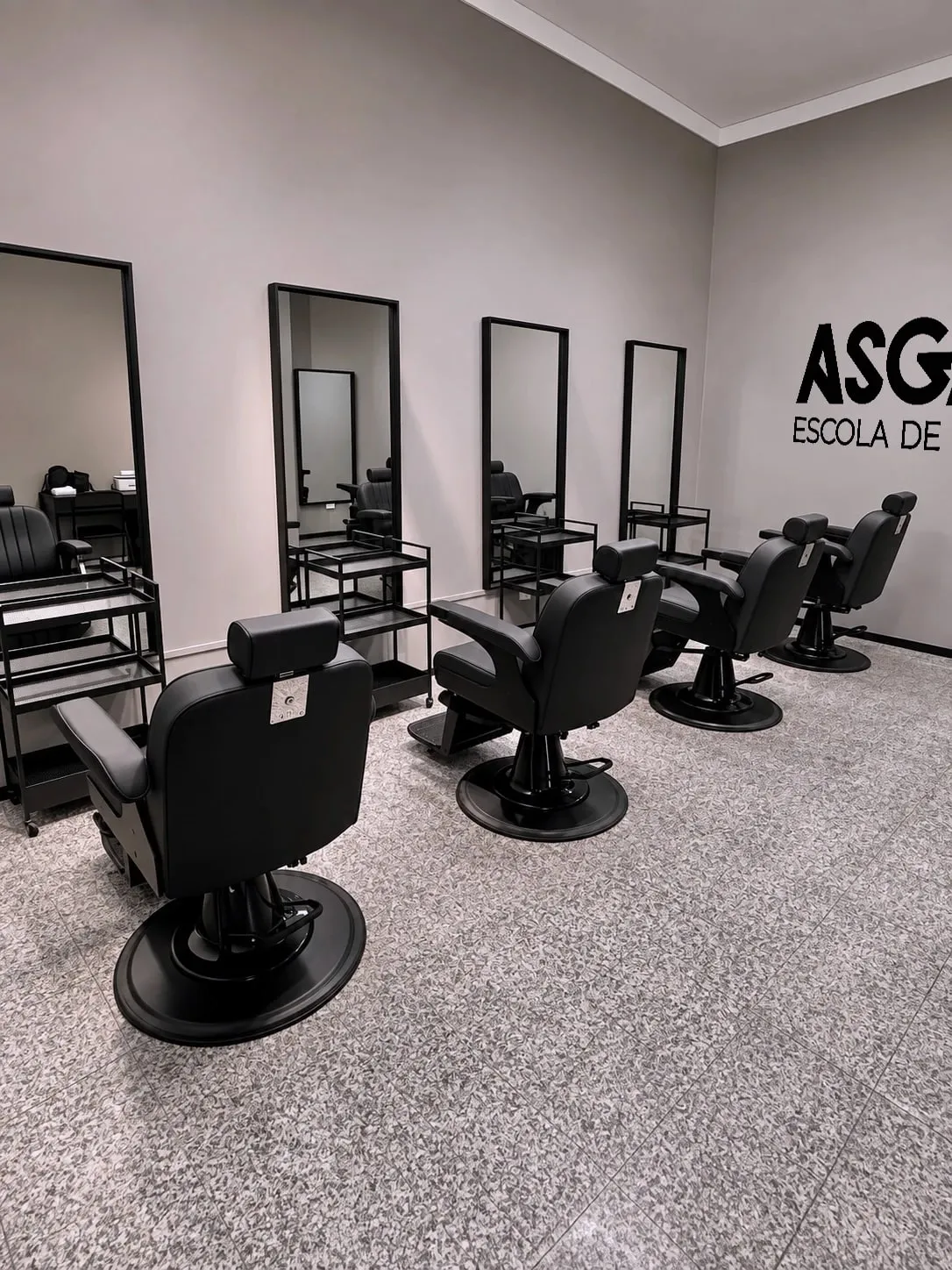 Sala da escola de barbeiros Asgard com cadeiras e espelhos