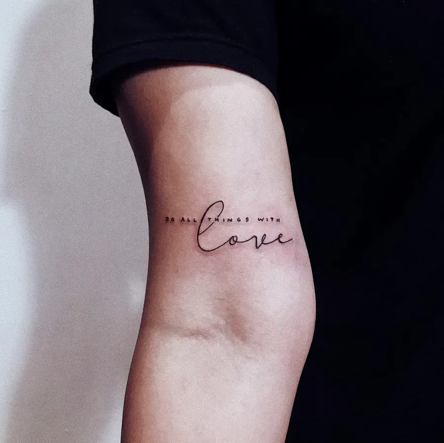 Tatuagem fine line com uma frase em letra cursiva no braço