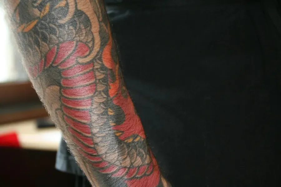 Tatuagem de estilo japonês com um dragão vermelho no braço