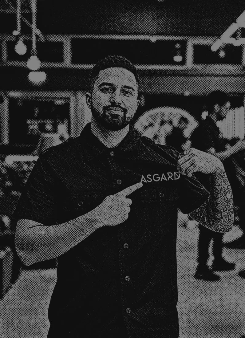 Barbeiro Asgard a apontar para o nome Asgard na camisa